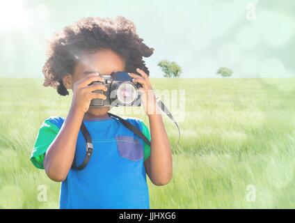 Junge mit Kamera gegen Wiese mit flare Stockfoto