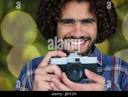 glückliche Fotograf mit Vintage-Kamera. Grüne und gelbe Lichter Hintergrund unscharf Stockfoto