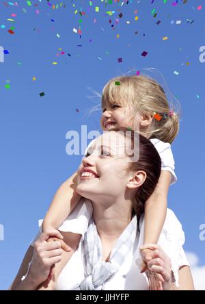 Konfetti gegen Tochter auf Mutters Schultern Stockfoto