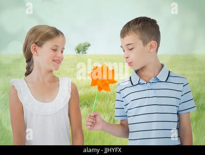 3D jungen und Mädchen mit Spielzeug Windmühle gegen Wiese Stockfoto