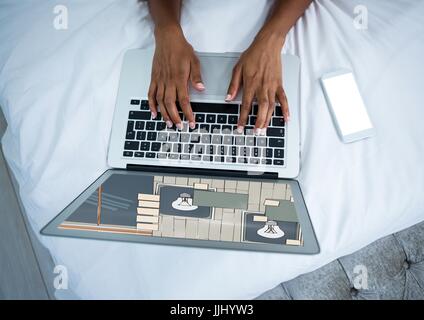Computer mit den Händen auf dem Bett. Auf dem Bildschirm das Design für die Wand. Stockfoto