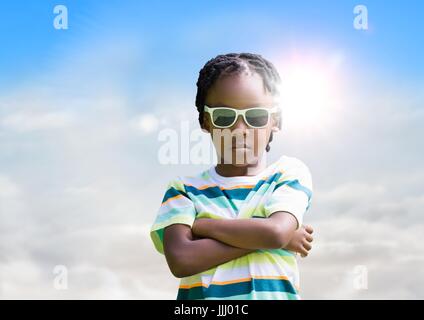 Jungen in Sonnenbrille Armen gefaltet gegen Himmel und Sonne mit flare Stockfoto