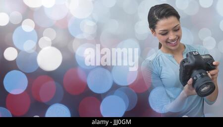 Fotografen, die ihre Kamera vor leuchtenden Hintergrund betrachten Stockfoto