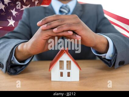 Business-Mann für ein Haus gegen amerikanische Flagge Stockfoto