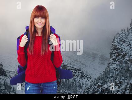 Tausendjährige Backpacker lächelnd vor schneebedeckten Bergen Stockfoto