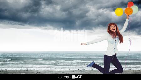 Frau mit Luftballons feiert am grauen Strand Stockfoto