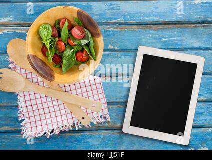 Tablet auf blauen hölzernen Schreibtisch mit Lebensmitteln 3d Stockfoto