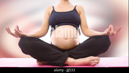 Schwangere Frau Mittelteil meditieren vor verschwommen roten und weißen abstrakten Hintergrund Stockfoto