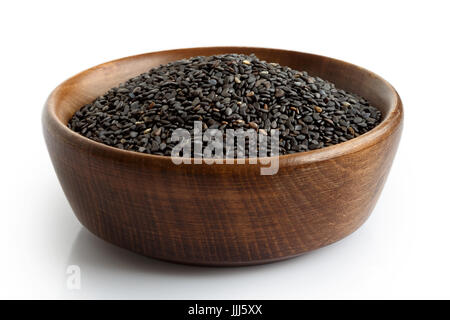 Schwarzer Sesam in dunklen Holzschale isoliert auf weiss. Stockfoto