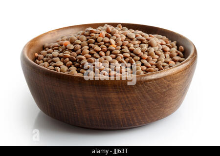 Trocken Sie ungeschälte rote Linsen in dunklen Holzschale isoliert auf weiss. Stockfoto