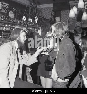 1970er Jahre, England, University Student trinken und reden in einer Bar, "Rag Week" zu feiern. Stockfoto