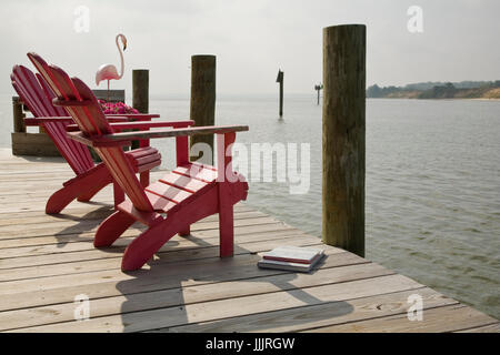 Beruhigender Blick auf rosa Adirondack Stühle mit Blick auf Körper des Wassers, rosa Flamingo, Deck, Piers. Urlaub, ruhig heiter Blick. Stockfoto