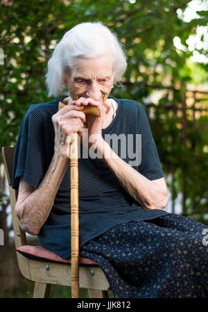 Fröhliche senior Frau sitzend mit einem Gehstock Stockfoto