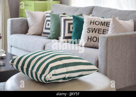 grün gestreiften Kissen auf dem gemütlichen grauen Sofa im Wohnzimmer Stockfoto