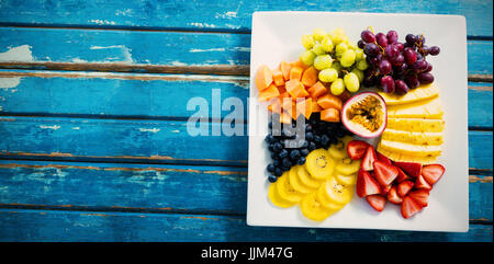 Frisches Obst im weißen Teller auf blaue Tabelle Stockfoto