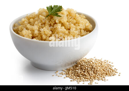 Gekochte Quinoa in weiße Keramikschale, isoliert auf weiss mit grüner Petersilie. Ungekocht Quinoa verschüttet. Stockfoto