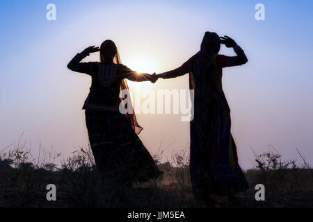 Zwei gypsy Frauen in Kleidern tanzen vor der untergehenden Sonne, Pushkar Camel Fair, Pushkar, Rajasthan, Indien Stockfoto