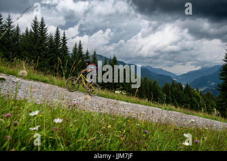 Ein Mountainbiker Fahrt mit einem elektrischen Pedal assist ebike bergauf in Morzine in den Französischen Alpen. Stockfoto