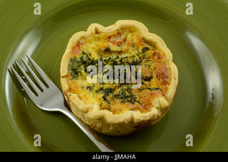 Individuellen Anteil Quiche Florentiner mit Spinat, Feta-Käse und Tomate in grüne Platte Stockfoto