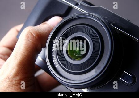 Foto von einer Hand hält eine spiegellose Digitalkamera Stockfoto