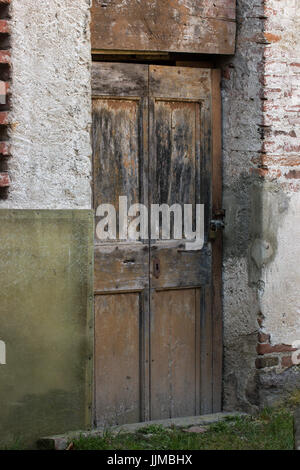 Einzelne alte Holztür mit der rustikalen Wand ruiniert Stockfoto