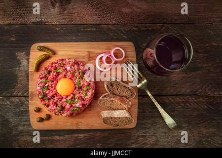 Steak Tartar mit Beilage, Rotwein und Exemplar Stockfoto