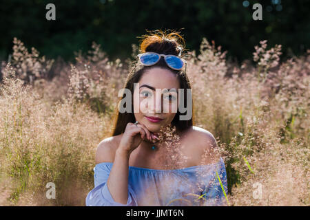 Eine junge Frau entspannt sich in einer sonnigen Wiese wildes Gras in der Nähe von Liverpool an einem Sommerabend. Stockfoto