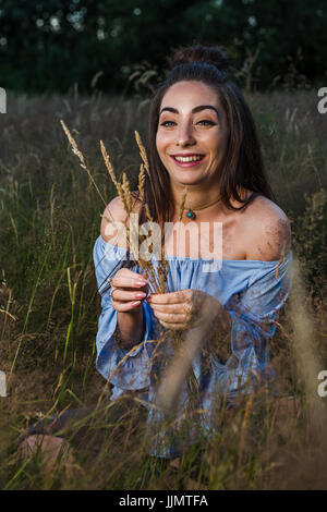 Mein Freund kichert während lange Strängen Gras auf einer Wiese in der Nähe von Liverpool zu pflücken. Stockfoto