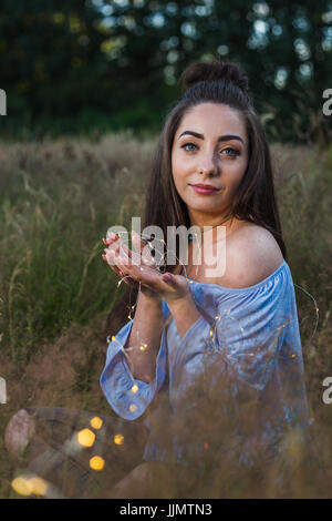 Mein Freund Tassen eine Reihe von Lichterketten in der Hand vor der Dämmerung während ein Outdoor-Portrait-Shooting in der Nähe von Liverpool. Stockfoto