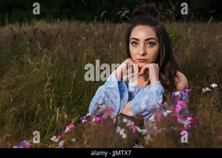 Mein Freund gibt einen ernsten Ausdruck auf ihrem Gesicht, während ein Outdoor-Portrait von einem Sommer Abend auf einer Wiese in der Nähe von Liverpool. Stockfoto