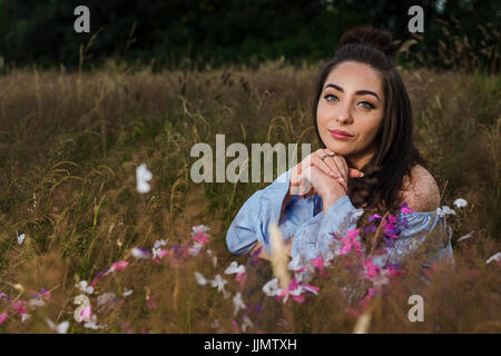 Mein Freund ruht ihr Kinn auf ihre Hände während einer Outdoor-Portrait-Session auf einer Wiese in der Nähe von Liverpool Wildgras. Stockfoto