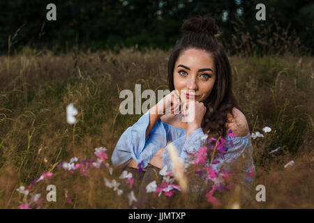 Mein Freund ruht ihr Kinn auf ihre Hände während einer Outdoor-Portrait-Session auf einer Wiese in der Nähe von Liverpool Wildgras. Stockfoto