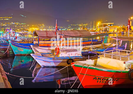 ALANYA, Türkei - 8. Mai 2017: Die Reihe der Fischerboote, im alten Hafen mit den hellen Lichtern der Nacht Stadt am Hintergrund, am 8. Mai in Turke angedockt Stockfoto