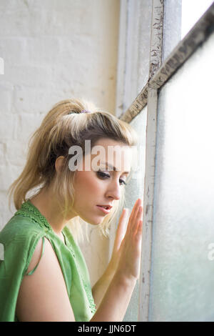 Traurige junge Frau Lookinng aus dem Fenster Stockfoto