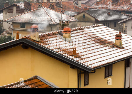 Drei moderne Beton Schornsteine mit Rauch aus dem Dach mit Schnee bedeckt Stockfoto