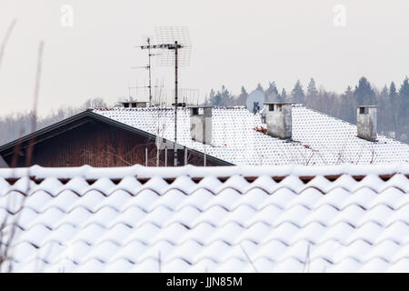 Drei konkrete Schornsteine mit Satellitenantenne und Schnee Stockfoto