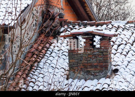 Große und alte gemauerte Schornstein mit Schnee, alte Dach mit großem Kamin Stockfoto