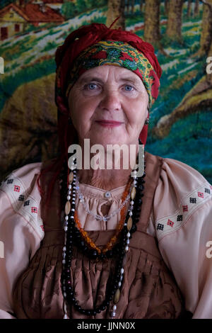 Eine ältere russische Frau in traditionellem Sarafankleid im Dorf Sibirjachiha, dessen Mitglieder die Bräuche und Traditionen der Altgläubigen mit hunderten von Jahren zurückreichenden Fundamenten bewahren, befindet sich im Bezirk Soloneshenskiy der Region Altai in Westsibirien, Russland. Die Alten Gläubigen oder Alten Ritualisten sind östliche orthodoxe Christen, die die liturgischen und rituellen Praktiken der russischen Kirche beibehalten, wie sie vor den Reformen des Patriarchen Nikon von Moskau zwischen 1652 und 1666 waren. Stockfoto