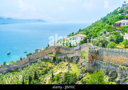 Die mittelalterlichen Festungsmauer verläuft entlang der Hänge des Burgbergs, teilt seine Gärten, Alanya, Türkei. Stockfoto