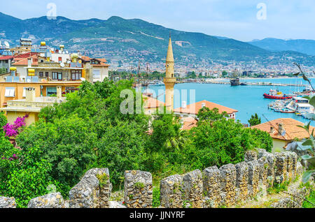 Der Blick auf den alten Yachthafen mit Küsten Gebäude, Minarett der Moschee Haci Kadiroglu, Cilician Berge und die Ruinen der Festung in Tophane Stockfoto