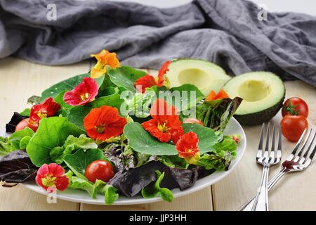 Frischer Salat mit Kapuzinerkresse Blüten, Cherry-Tomaten und Avocado. Selektiven Fokus mit extrem geringen Schärfentiefe. Stockfoto