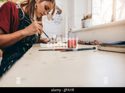 Bild der schönen Frau zeichnen von Bildern in ihrem Atelier. Künstlerin im Atelier malen. Stockfoto