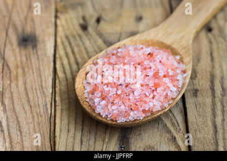 Rosa Himalayasalz in Holzlöffel auf Plank Holz Hintergrund, Nahaufnahme, gesunde Ernährung, Wellness, Ayurveda-Konzept Stockfoto