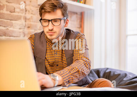 Junger Mann tragen Brille sitzt vor einem Laptop und arbeiten. Stockfoto