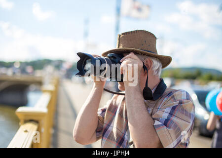 Senior Tourist Mann in Hut fotografieren während der Fahrt auf Brücke Stockfoto