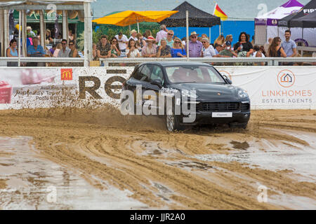 Charity-Rennen zwischen einem Porsche Wagen und Pferd findet statt am Strand bei den British Beach Polo Championships auf Sandbänken Strand, Poole Dorset im Juli Stockfoto