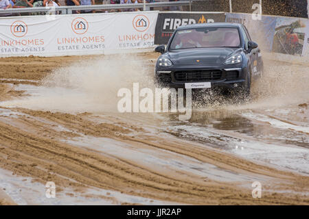 Charity-Rennen zwischen einem Porsche Wagen und Pferd findet statt am Strand bei den British Beach Polo Championships auf Sandbänken Strand, Poole Dorset im Juli Stockfoto