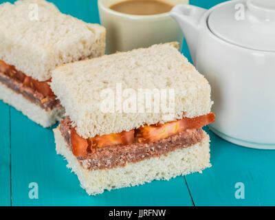 Corned Beef und Tomatenmark Weißbrot Sandwich vor einem blauen Hintergrund Stockfoto