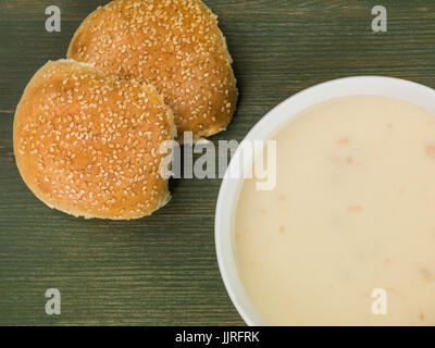 Schüssel mit Creme der Hühnersuppe mit Brot Brötchen vor einem grünen Hintergrund Stockfoto