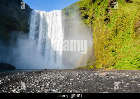 Berühmte Skogafoss Wasserfall in Island mit Regenbogen an sonnigen Sommertag, niemand im Foto. Stockfoto